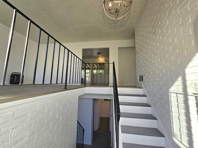 stairs with a textured ceiling and brick wall