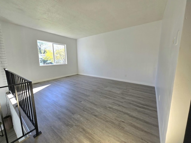 spare room featuring dark hardwood / wood-style flooring and a textured ceiling