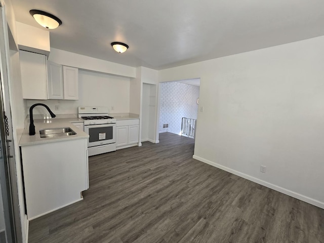 kitchen with white gas range, dark hardwood / wood-style floors, sink, and white cabinets