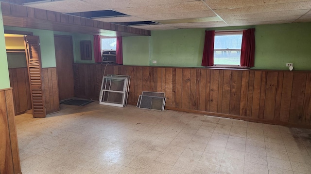 basement with a paneled ceiling and wooden walls