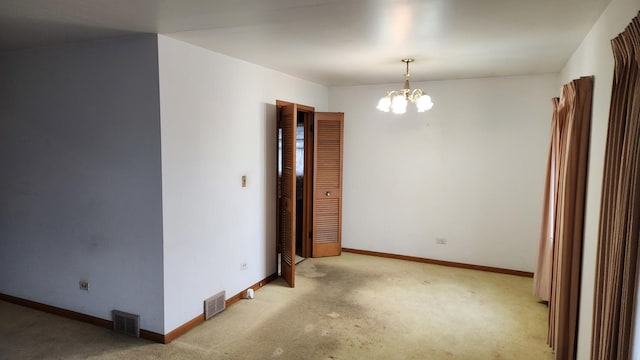 carpeted spare room featuring an inviting chandelier