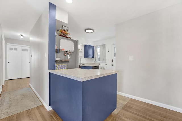 kitchen with blue cabinets, kitchen peninsula, and hardwood / wood-style flooring