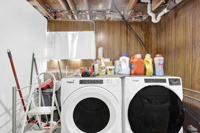 laundry area featuring wood walls and washing machine and clothes dryer