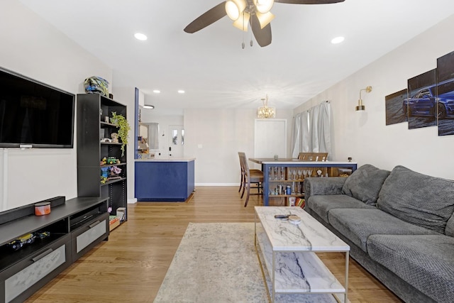 living room featuring ceiling fan with notable chandelier and light hardwood / wood-style floors