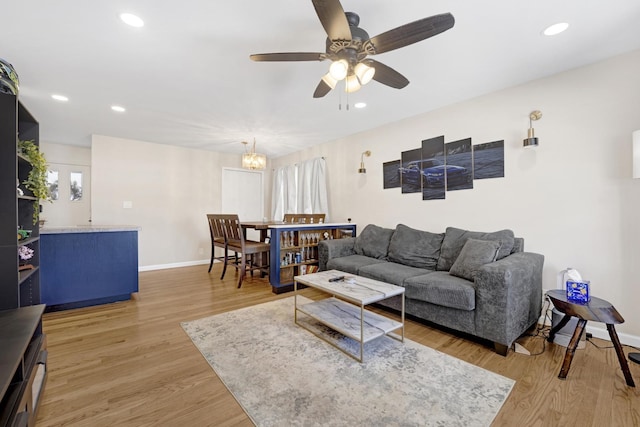 living room featuring ceiling fan with notable chandelier, wood-type flooring, and plenty of natural light