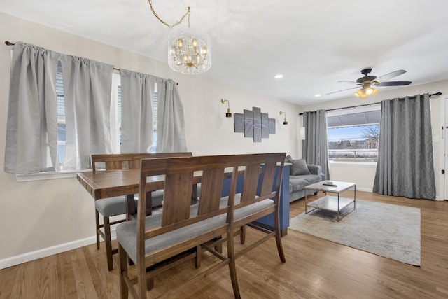 dining room with ceiling fan with notable chandelier and hardwood / wood-style flooring