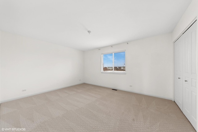 unfurnished bedroom featuring a closet and light colored carpet