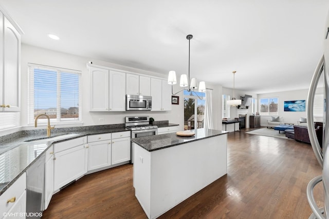 kitchen featuring pendant lighting, a kitchen island, sink, white cabinetry, and stainless steel appliances