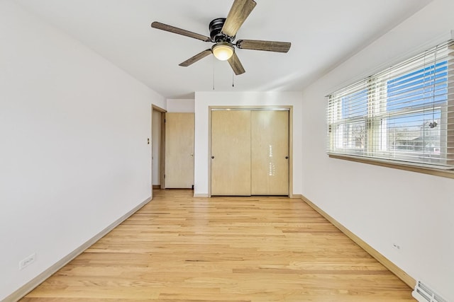 unfurnished bedroom featuring ceiling fan, a baseboard radiator, light hardwood / wood-style floors, and a closet