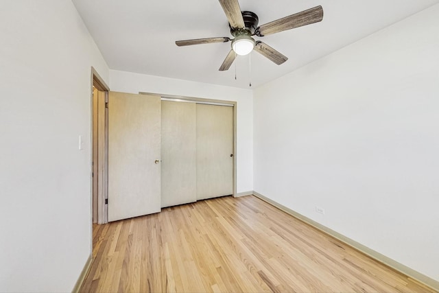 unfurnished bedroom featuring ceiling fan, a closet, and light wood-type flooring