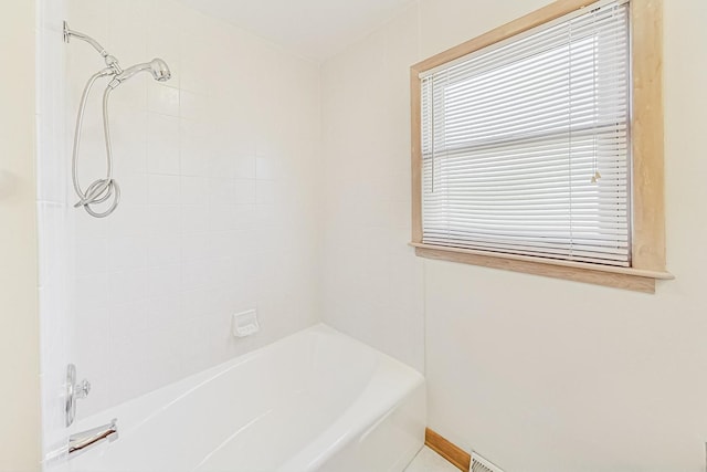 bathroom featuring tiled shower / bath combo and tile patterned flooring