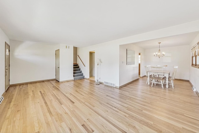 unfurnished living room with an inviting chandelier and light wood-type flooring