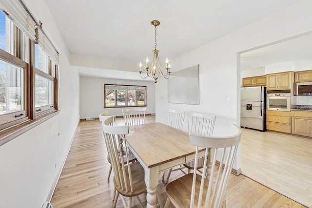 dining area with an inviting chandelier and light hardwood / wood-style floors