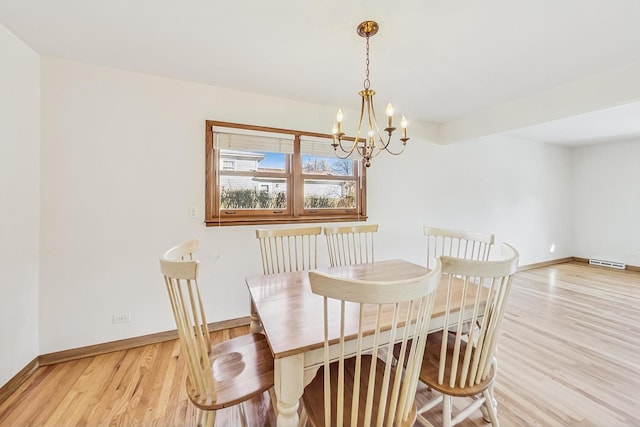 dining area with a notable chandelier and light hardwood / wood-style flooring