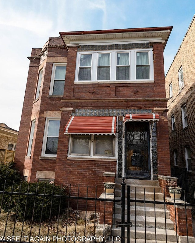 view of front of property featuring a fenced front yard and brick siding