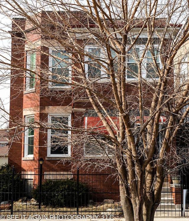 view of side of property with a fenced front yard and brick siding