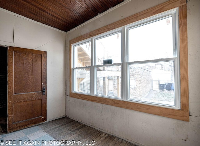 unfurnished room with a wealth of natural light, wooden ceiling, and wood finished floors