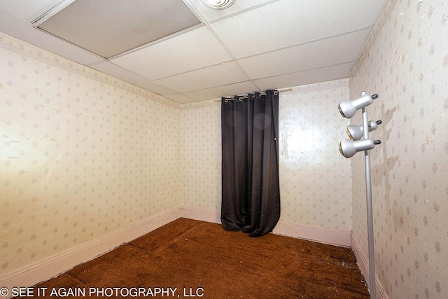 empty room featuring a drop ceiling, baseboards, and wallpapered walls