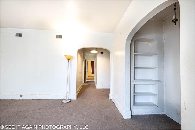 corridor featuring visible vents, arched walkways, and built in features