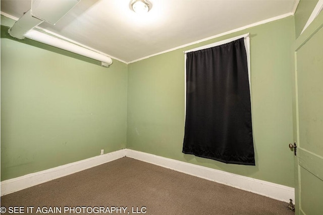 carpeted empty room featuring crown molding and baseboards