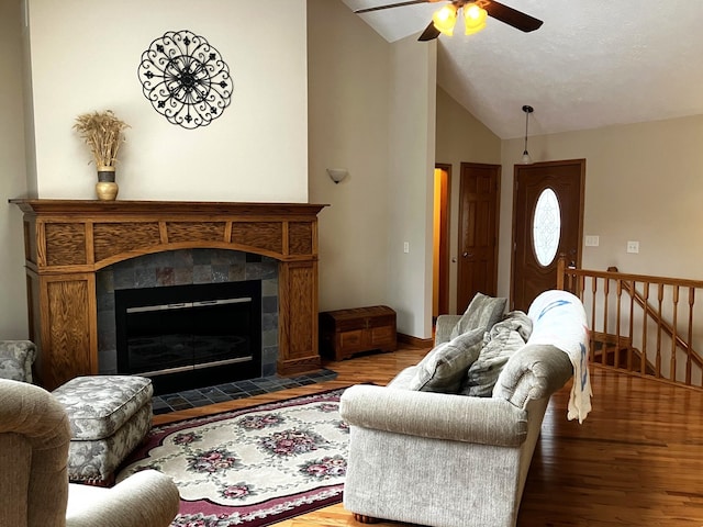 living room featuring a tiled fireplace, hardwood / wood-style flooring, ceiling fan, and vaulted ceiling