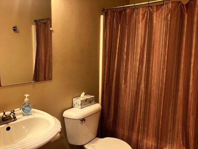 bathroom with toilet, a shower with shower curtain, and sink