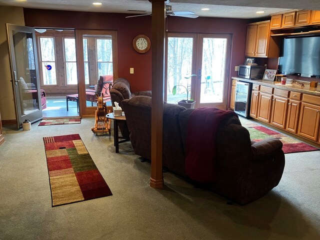 carpeted living room with a healthy amount of sunlight, ceiling fan, french doors, and wine cooler