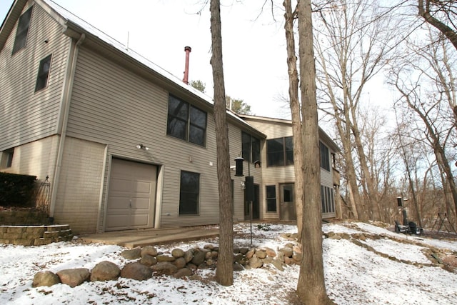 snow covered house featuring a garage