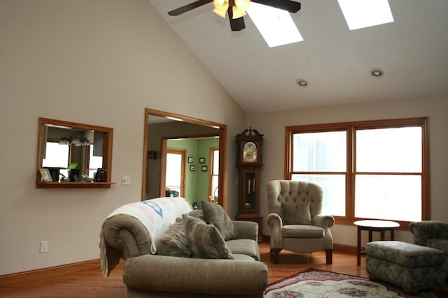 living room featuring ceiling fan, light hardwood / wood-style flooring, a skylight, and plenty of natural light