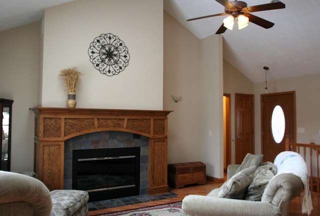 living room featuring a tile fireplace, lofted ceiling, ceiling fan, light hardwood / wood-style flooring, and a wealth of natural light