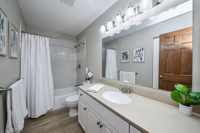 full bathroom with hardwood / wood-style flooring, vanity, shower / bathtub combination with curtain, and toilet