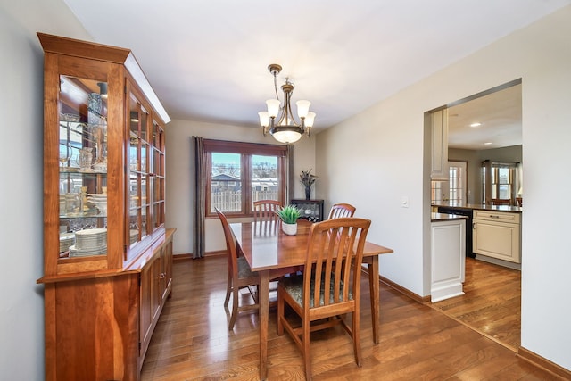 dining room with dark wood-type flooring and an inviting chandelier