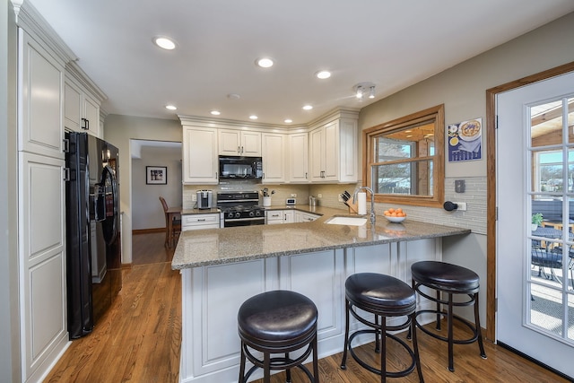 kitchen featuring sink, backsplash, black appliances, white cabinets, and kitchen peninsula