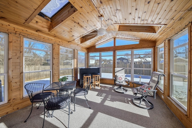 sunroom / solarium featuring vaulted ceiling with skylight and wooden ceiling