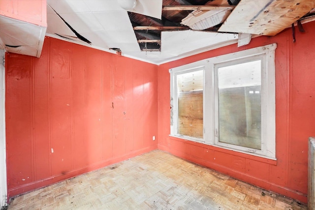 unfurnished room with wood walls and light parquet flooring