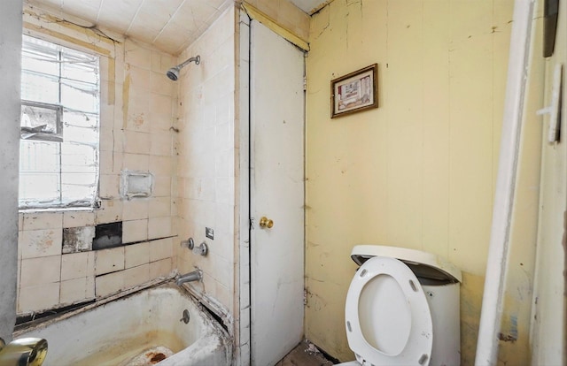 bathroom featuring toilet, tiled shower / bath combo, and a wealth of natural light