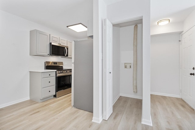 kitchen with gray cabinetry, stainless steel appliances, and light hardwood / wood-style floors