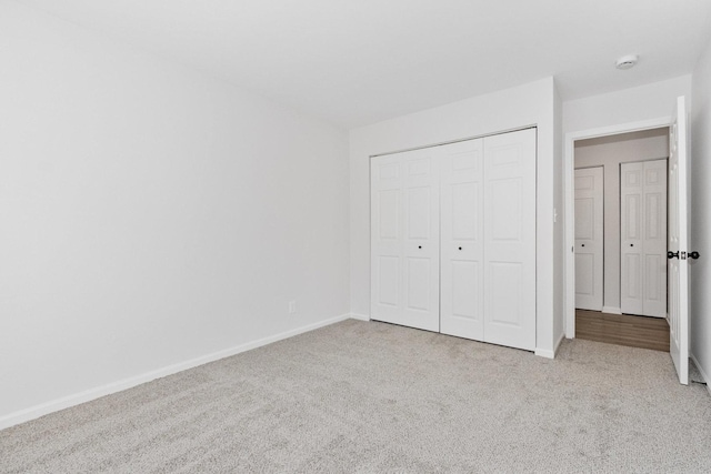 unfurnished bedroom with light colored carpet and a closet