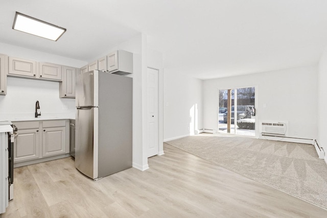 kitchen featuring gray cabinets, stainless steel fridge, a baseboard heating unit, sink, and light hardwood / wood-style flooring