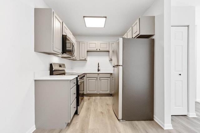 kitchen featuring stainless steel appliances, light wood-type flooring, gray cabinets, and sink