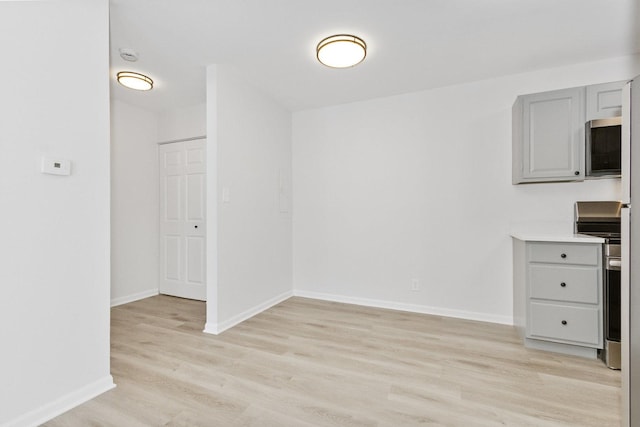 kitchen featuring appliances with stainless steel finishes, light hardwood / wood-style flooring, and gray cabinets