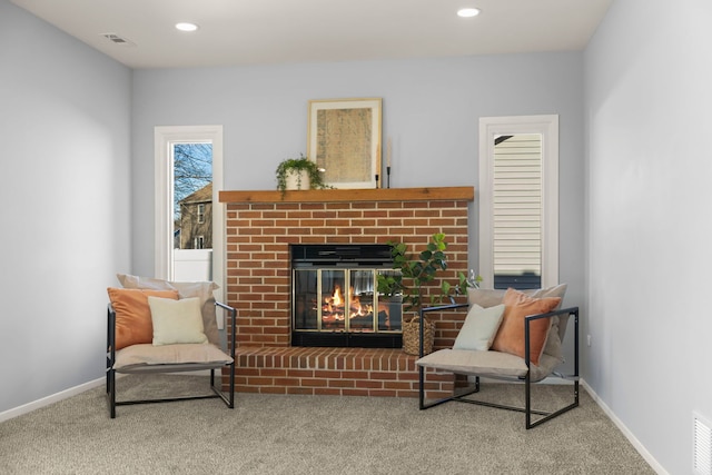 sitting room with a brick fireplace and carpet floors