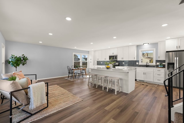 kitchen with a breakfast bar area, backsplash, a center island, a healthy amount of sunlight, and white cabinets