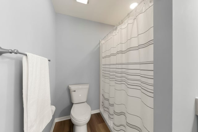 bathroom featuring walk in shower, hardwood / wood-style floors, and toilet