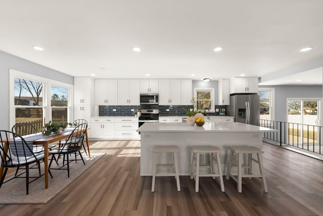 kitchen featuring a kitchen island, a breakfast bar, white cabinets, and appliances with stainless steel finishes