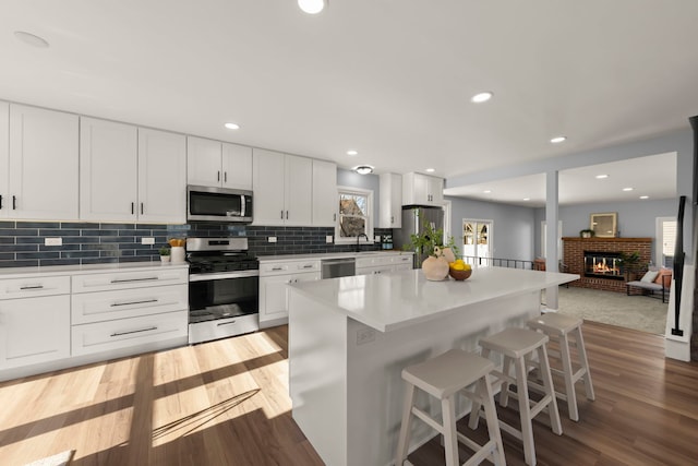 kitchen with stainless steel appliances, a breakfast bar, white cabinets, and a kitchen island