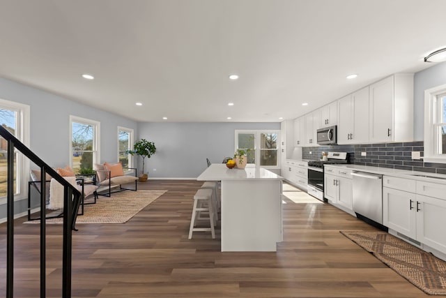 kitchen with stainless steel appliances, a kitchen breakfast bar, white cabinets, and a kitchen island