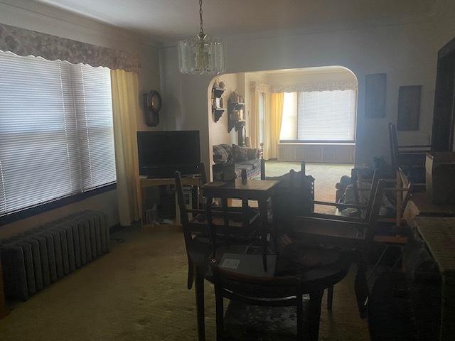 dining room with an inviting chandelier, radiator heating unit, and carpet flooring