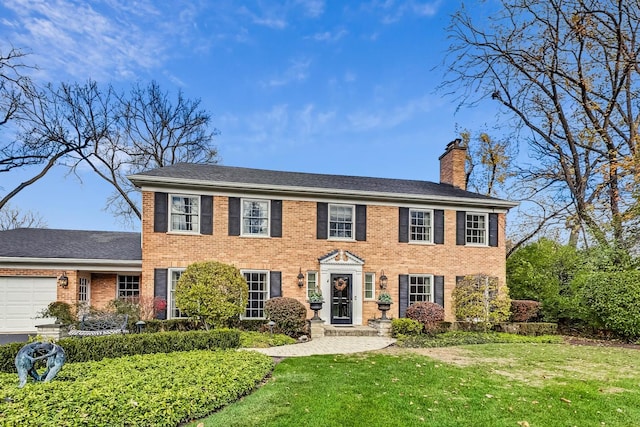 colonial inspired home with a garage and a front lawn