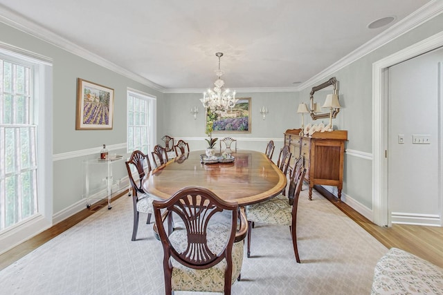 dining area with light hardwood / wood-style flooring, crown molding, and a notable chandelier